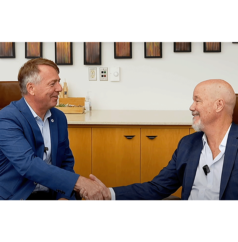 Two people shaking hands while smiling in an office