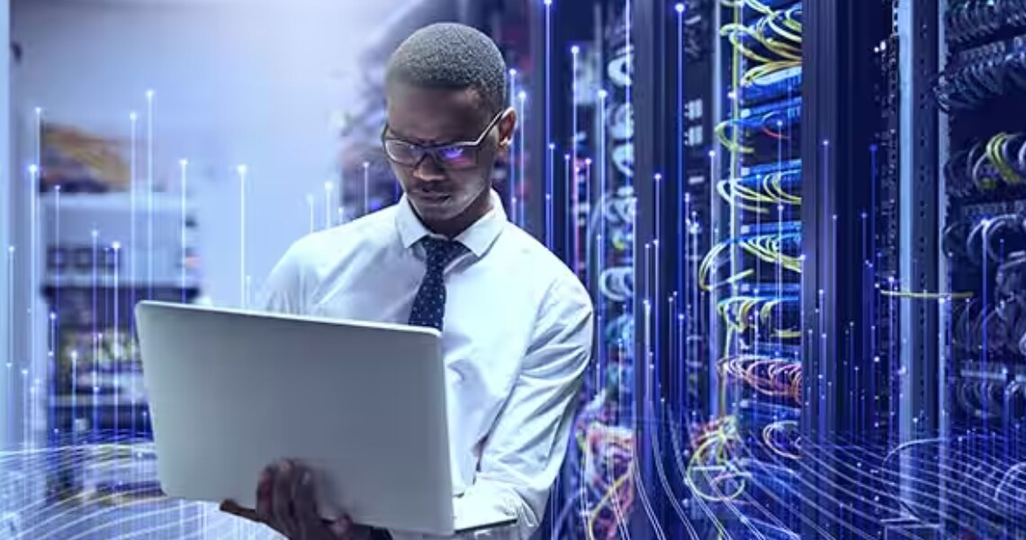 A man using a laptop while standing in a data center