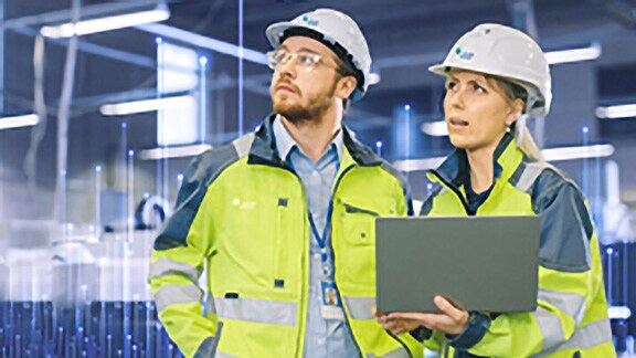 A male and a female Johnson Controls technician using a laptop, overlaid with a graphic of transmission nodes in the backgroound