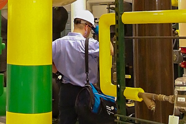 Man with a duffel bag inspecting a machine